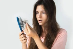 Mulher preocupada segurando escova com queda de cabelo feminina, imagem de destaque do blog Beleza em Foco.