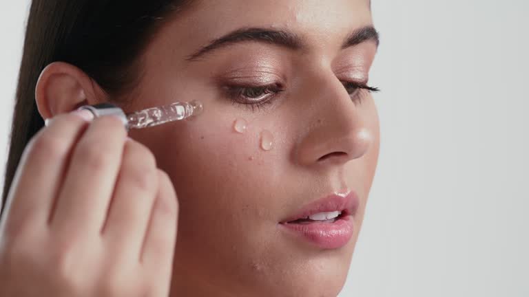 Textura aquosa e transparente de sérum de niacinamida sendo aplicado no rosto com pipeta.