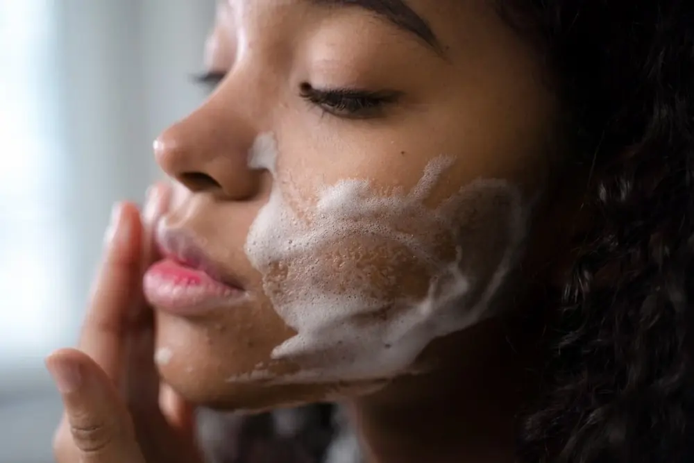Mulher aplicando gel de limpeza suave no rosto para recuperar a barreira cutânea.