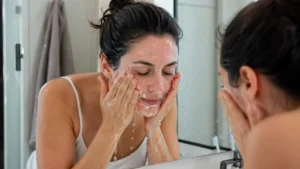 Mulher lavando o rosto durante a rotina de skincare para escolher entre o GL-01 e o GL-02 da Principia.