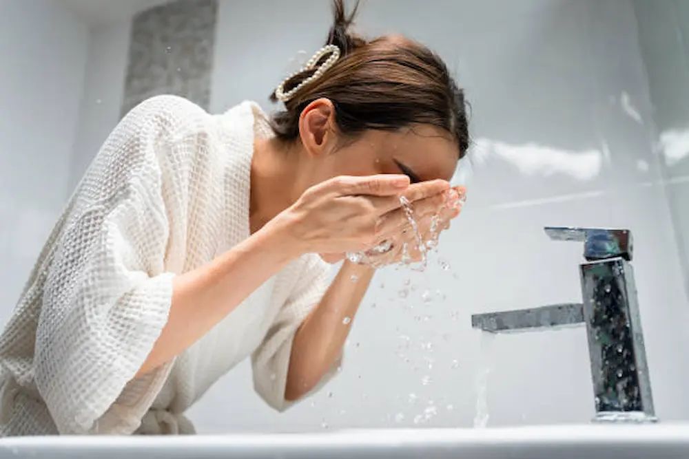 Mulher realizando a limpeza facial como primeiro passo da rotina de skincare.