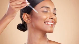 Mulher aplicando sérum com conta-gotas e pele radiante após Skin Cycling