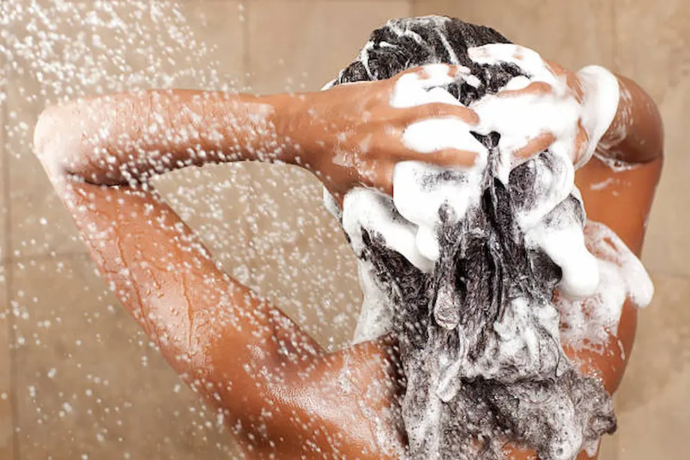 Mulher lavando o cabelo corretamente durante a rotina de scalp care para manter o couro cabeludo saudável.
