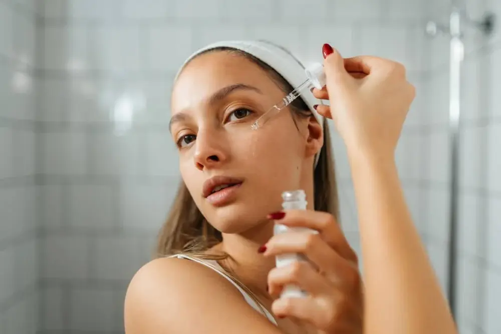 Mulher aplicando sérum facial antes do hidratante durante a rotina de skincare.